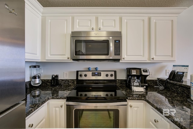 kitchen with dark stone countertops, white cabinetry, a textured ceiling, and appliances with stainless steel finishes