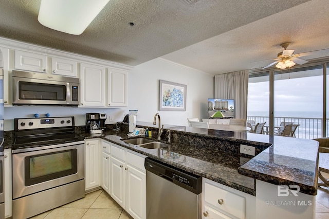 kitchen featuring kitchen peninsula, stainless steel appliances, white cabinetry, and sink