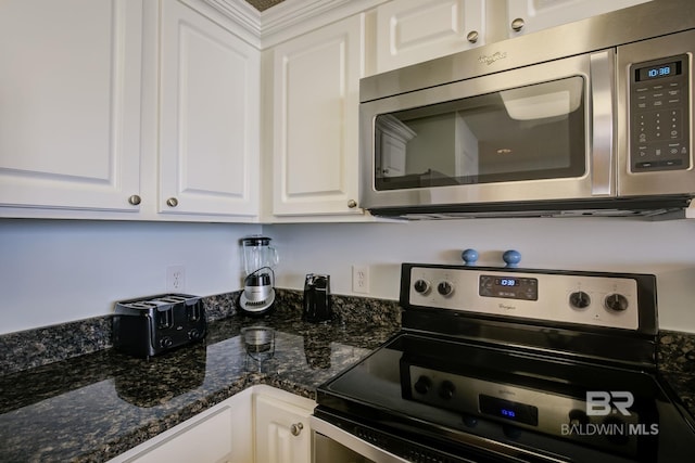 kitchen with dark stone countertops, white cabinetry, and black / electric stove