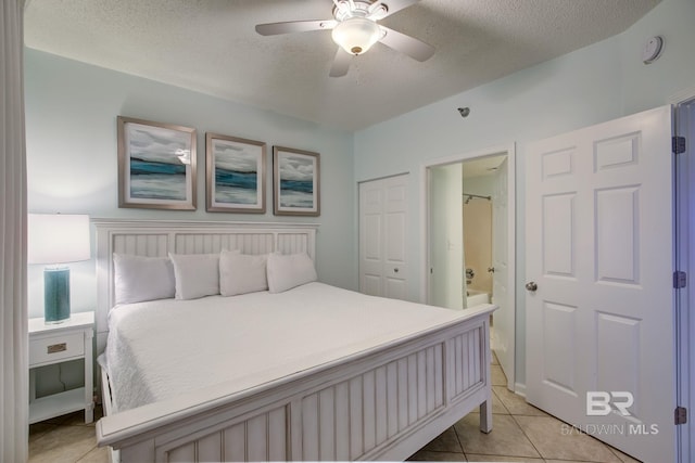 bedroom featuring ensuite bathroom, a textured ceiling, ceiling fan, light tile patterned floors, and a closet