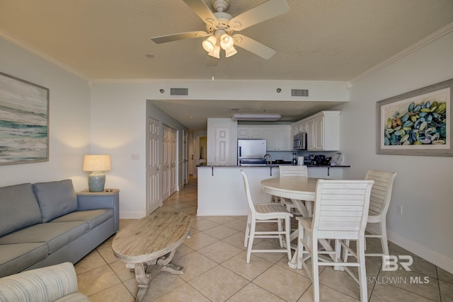 dining room with ceiling fan, light tile patterned floors, a textured ceiling, and ornamental molding