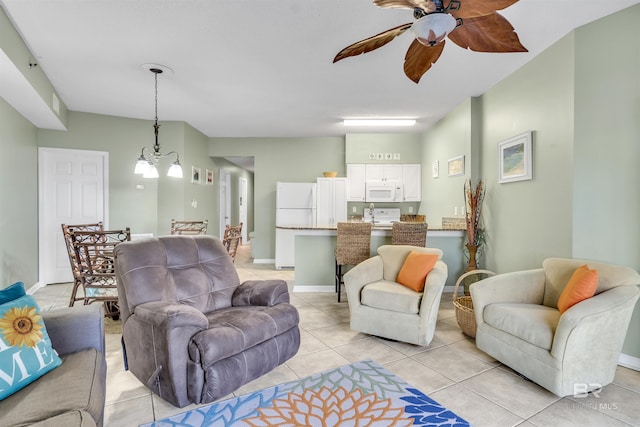 living room featuring ceiling fan with notable chandelier, light tile patterned flooring, and baseboards