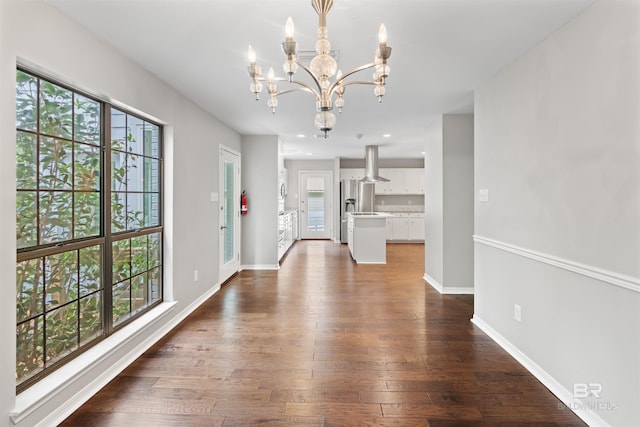 unfurnished dining area with dark wood-type flooring, a healthy amount of sunlight, and a notable chandelier