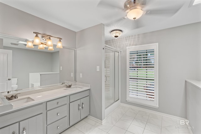 bathroom with a shower with door, vanity, toilet, and ceiling fan