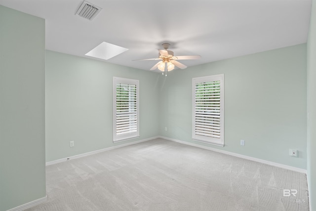 unfurnished room featuring a wealth of natural light, light colored carpet, ceiling fan, and a skylight