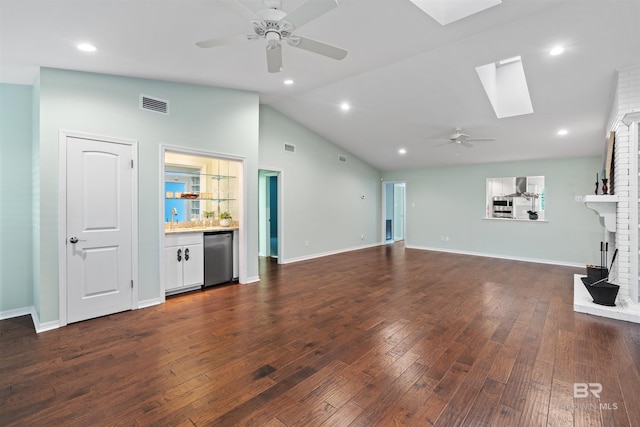 unfurnished living room with a fireplace, ceiling fan, dark hardwood / wood-style floors, and a skylight