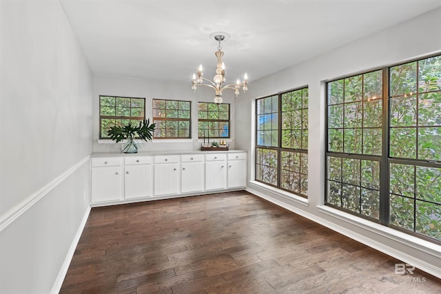 interior space with dark wood-type flooring, white cabinetry, a notable chandelier, and pendant lighting