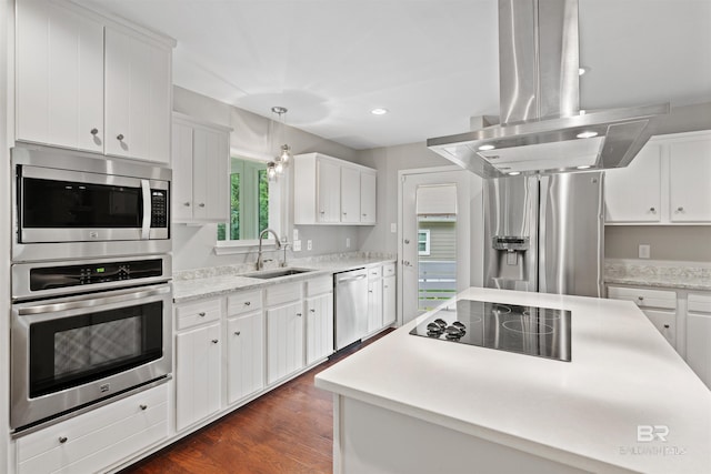 kitchen with pendant lighting, appliances with stainless steel finishes, island exhaust hood, sink, and white cabinets