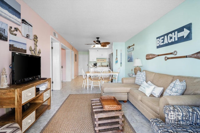 living room with ceiling fan and a textured ceiling