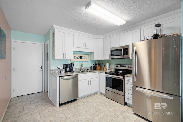 kitchen with white cabinetry, light stone countertops, a textured ceiling, sink, and stainless steel appliances