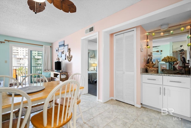 tiled dining area featuring a textured ceiling and ceiling fan