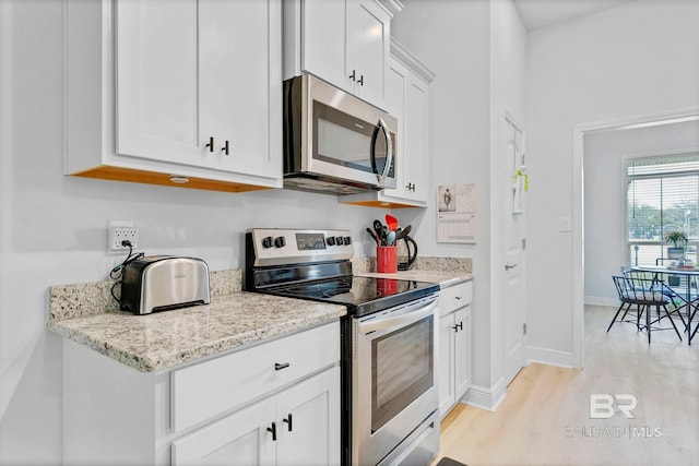 kitchen featuring baseboards, light stone countertops, appliances with stainless steel finishes, white cabinetry, and light wood-style floors