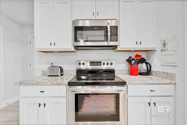 kitchen with white cabinets, stainless steel appliances, and light stone counters
