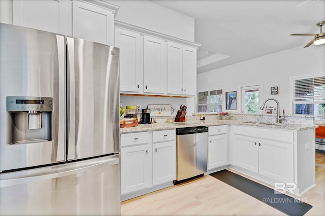 kitchen with white cabinetry, stainless steel appliances, a sink, a ceiling fan, and a peninsula