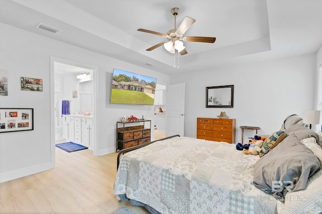 bedroom with baseboards, a raised ceiling, light wood finished floors, ceiling fan, and visible vents