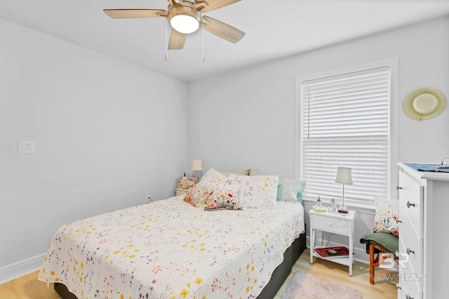 bedroom featuring baseboards, multiple windows, ceiling fan, and light wood-type flooring