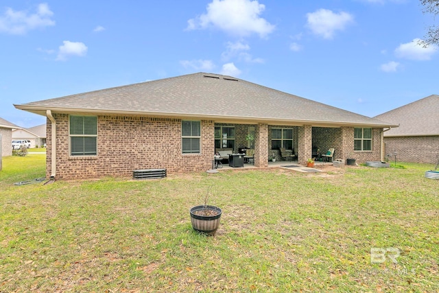 back of house featuring brick siding, roof with shingles, a yard, and a patio area