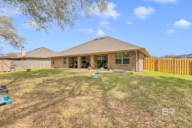 rear view of house with brick siding, a fenced backyard, and a yard