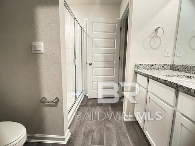 bathroom featuring hardwood / wood-style floors, vanity, toilet, and an enclosed shower