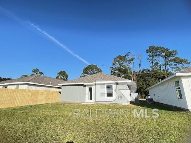 back of property with central air condition unit and a yard