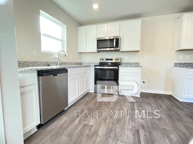 kitchen featuring light hardwood / wood-style flooring, white cabinets, and stainless steel appliances