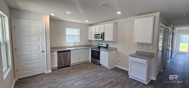 kitchen with white cabinetry, stainless steel appliances, a textured ceiling, and dark hardwood / wood-style flooring