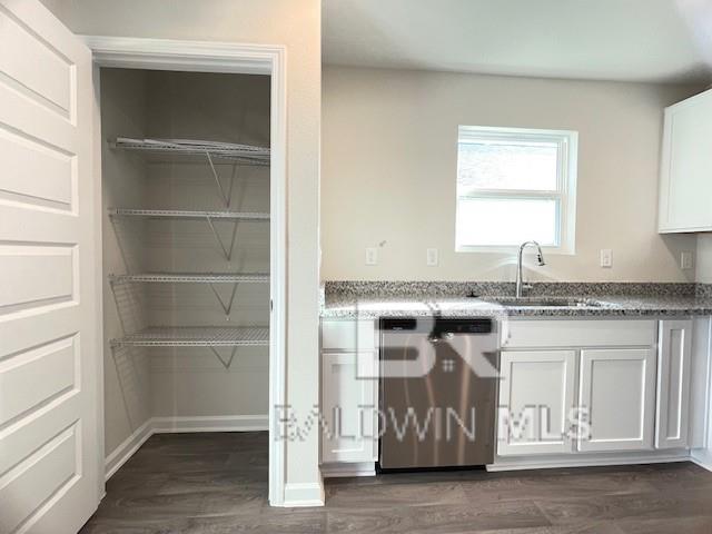 kitchen featuring dark hardwood / wood-style flooring, sink, white cabinets, dishwasher, and dark stone countertops