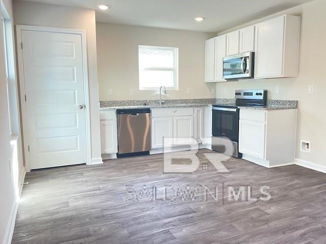 kitchen featuring white cabinets, appliances with stainless steel finishes, and hardwood / wood-style flooring