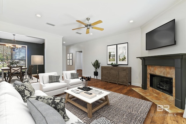 living room with a high end fireplace, ceiling fan with notable chandelier, hardwood / wood-style flooring, and crown molding