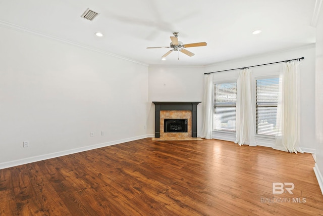 unfurnished living room featuring hardwood / wood-style floors, ceiling fan, ornamental molding, and a tile fireplace