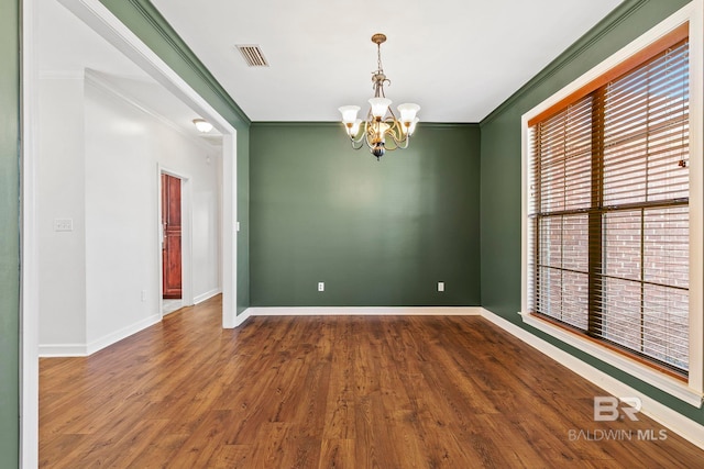 unfurnished room featuring a notable chandelier, wood finished floors, visible vents, baseboards, and ornamental molding