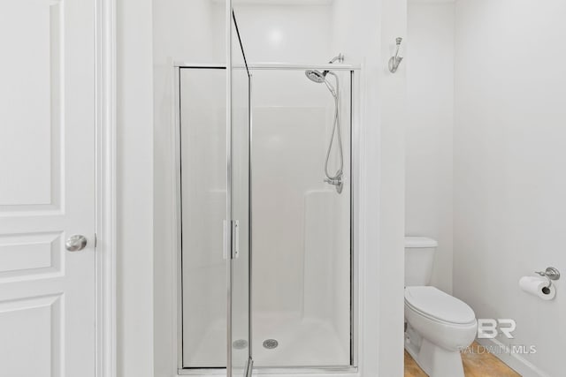 bathroom featuring toilet and a shower with door