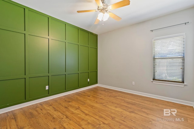 empty room with light wood finished floors, a ceiling fan, and baseboards