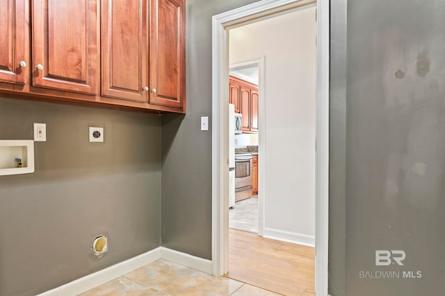 washroom featuring light tile patterned floors, hookup for a washing machine, cabinet space, electric dryer hookup, and baseboards