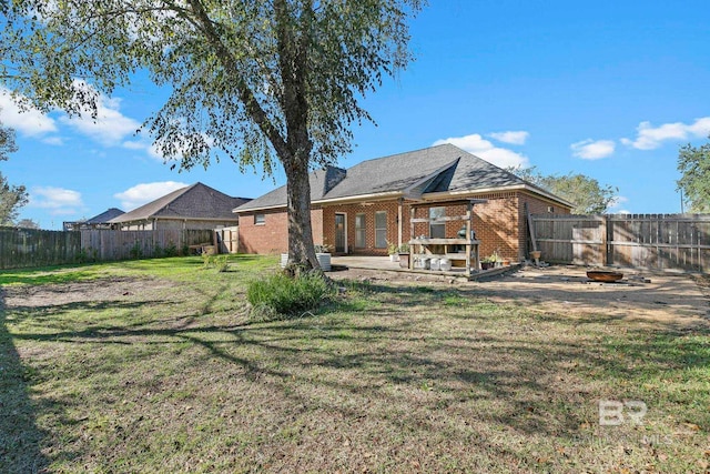 back of property featuring brick siding, a fenced backyard, a patio area, and a yard