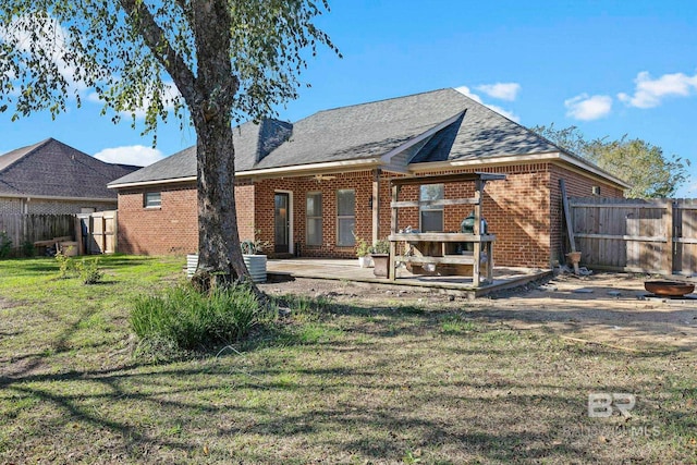 back of house with brick siding, a yard, a shingled roof, a patio area, and a fenced backyard