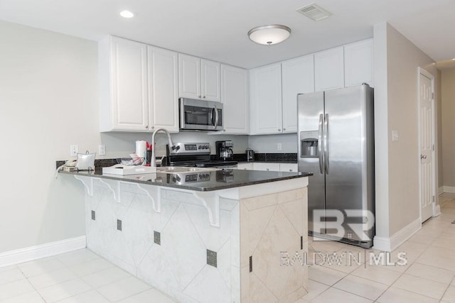 455 E Beach Blvd Unit 1505, Gulf Shores, AL 36542 - kitchen with appliances with stainless steel finishes, white cabinets, a kitchen bar, visible vents, and a peninsula