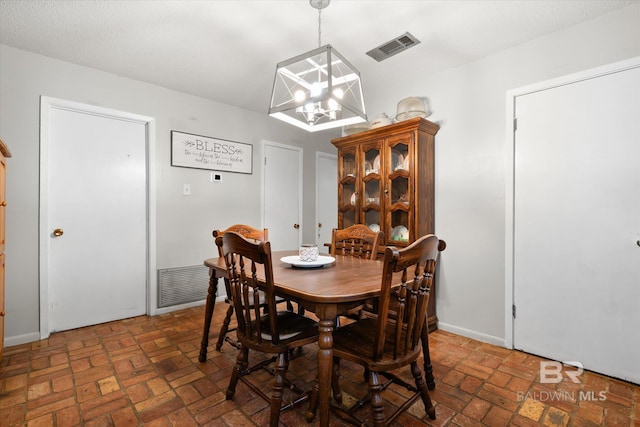 dining area with an inviting chandelier and a textured ceiling