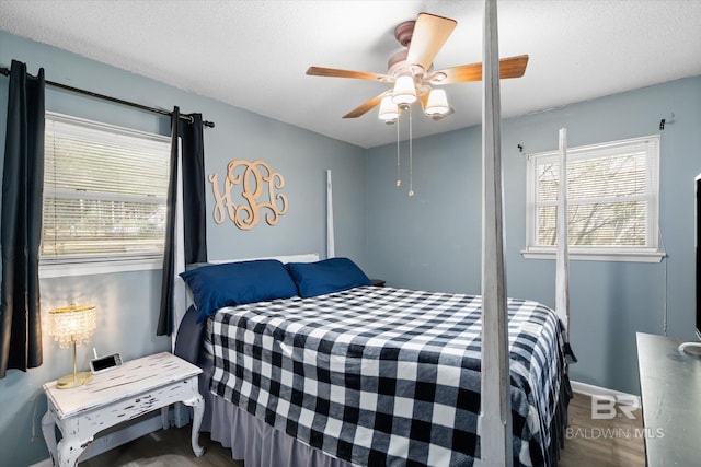 bedroom with hardwood / wood-style floors, ceiling fan, and a textured ceiling