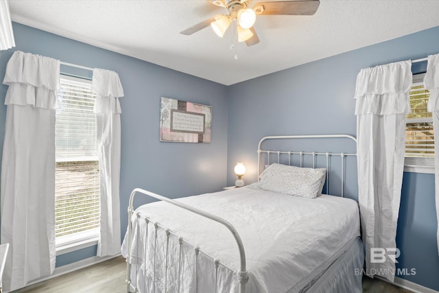 bedroom featuring light hardwood / wood-style flooring, ceiling fan, and a textured ceiling