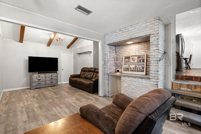 living room with a textured ceiling, vaulted ceiling with beams, and light wood-type flooring