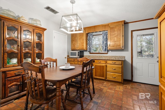 dining room featuring a healthy amount of sunlight, a chandelier, and a textured ceiling