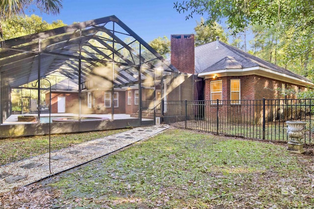 back of house with a lawn, glass enclosure, and a patio