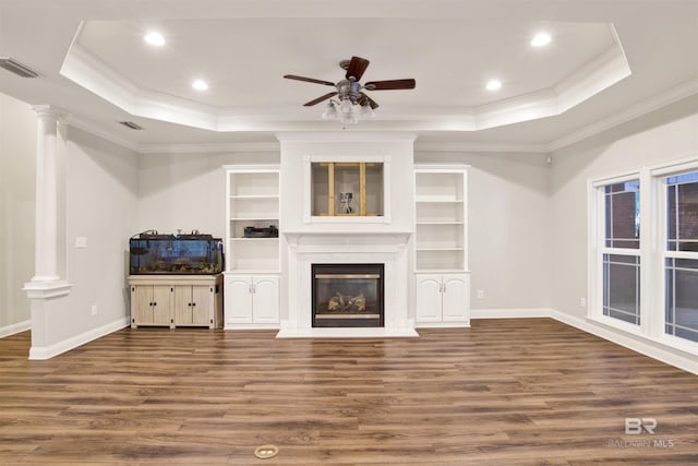 unfurnished living room with a tray ceiling, crown molding, ceiling fan, and dark wood-type flooring