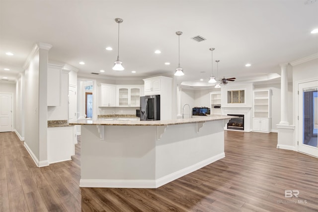 kitchen featuring a spacious island, white cabinets, decorative light fixtures, and stainless steel refrigerator with ice dispenser