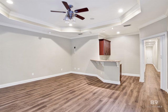 spare room with a tray ceiling, crown molding, ceiling fan, and wood-type flooring