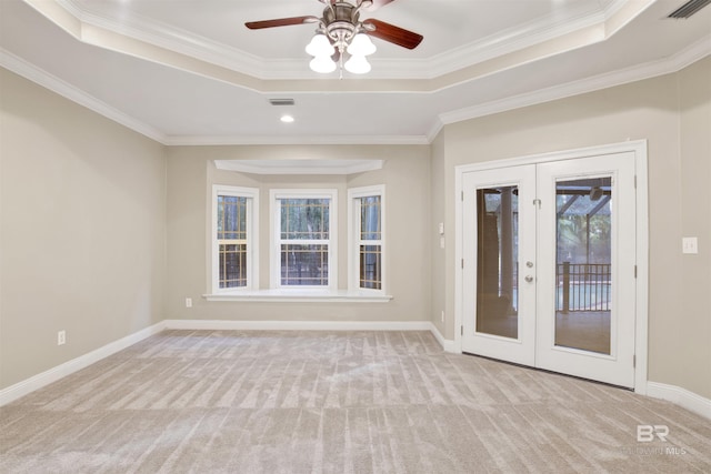 carpeted empty room with ceiling fan, french doors, crown molding, and a tray ceiling