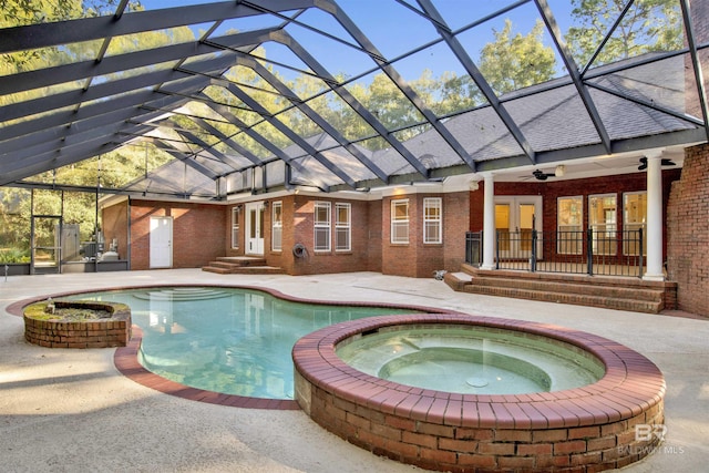 view of swimming pool featuring an in ground hot tub, glass enclosure, ceiling fan, and a patio area