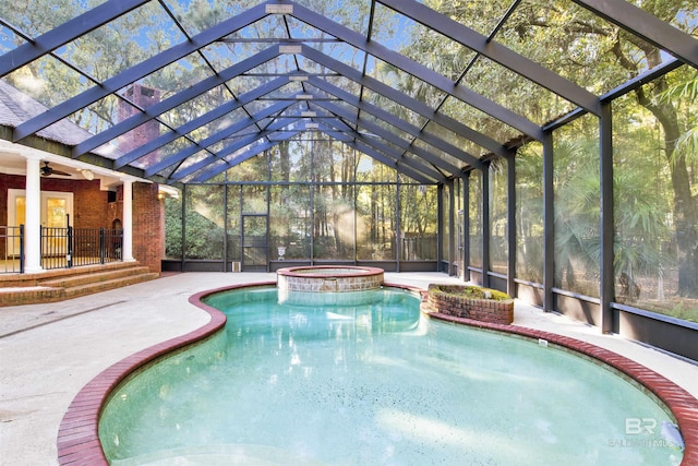 view of pool featuring glass enclosure, an in ground hot tub, a patio area, and ceiling fan