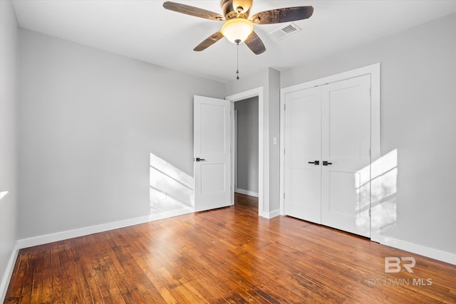 unfurnished bedroom featuring hardwood / wood-style floors, a closet, and ceiling fan